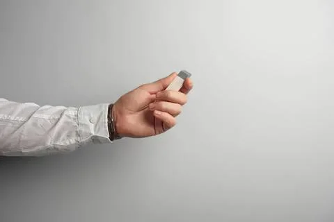 Hand holding small gray remote control device against plain background Stock Photos