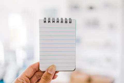 Hand holding small notepad with blank copy space in front of stylish living.. Stock Photos