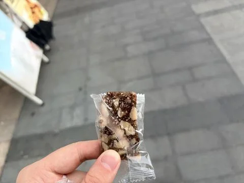 Hand Holding Small Packaged Nut and Chocolate Snack Outdoors Stock Photos