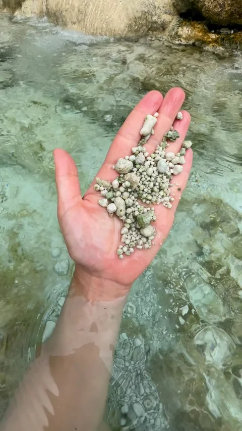 Hand holding small pebbles from clear water of a natural hot spring in Canada 動画素材 333011910