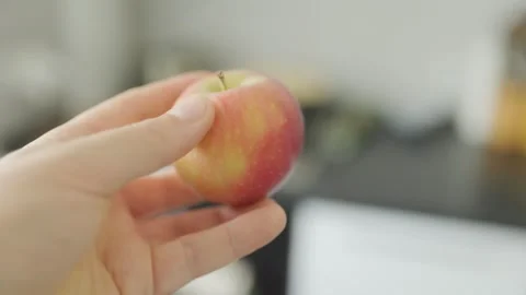 Hand Holding a Small Red and Yellow Apple Indoors with Soft Light Stock Footage 306440968