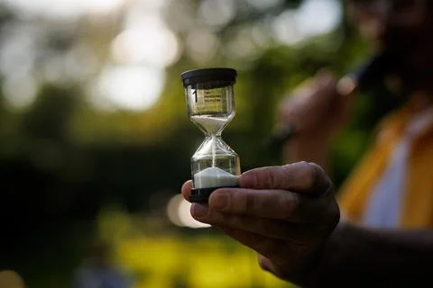 Hand holding small sand timer outdoors Stock-Fotos