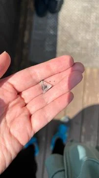 Hand holding small triangular piece of clear glass, showcasing intricate de.. 스톡 사진