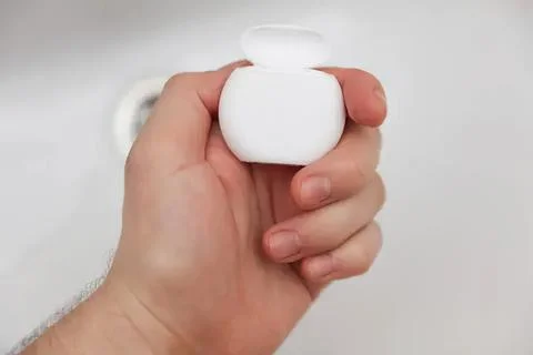 Hand holding a small white container with lid Fotos de archivo