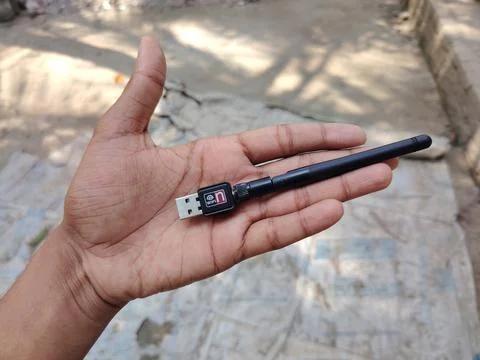 Hand holding a small wireless USB WiFi adapter outdoors on a sunny day Fotos Stock