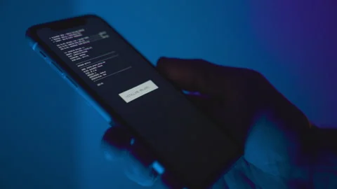 Hand holding smart phone on dark blue background while malware app is installed Stock Footage 324738370