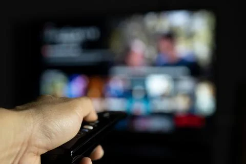 Hand holding smart TV remote control watch movies at night Stock Photos