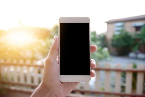 Hand holding smartphone against house on background Stock Photos