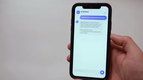 Hand holding smartphone with AI chatbot app answering a typed question Video stock 342603394