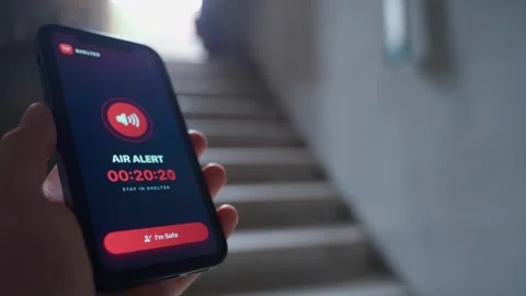Hand holding smartphone with air raid alert app showing warning timer in Stock Footage 340388619
