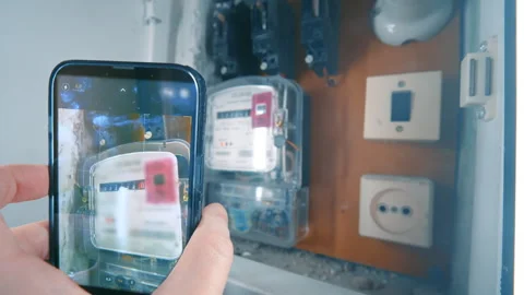 Hand Holding Smartphone and Taking Photo of Electric Meter Readings | Tracking Stock Footage 333079839