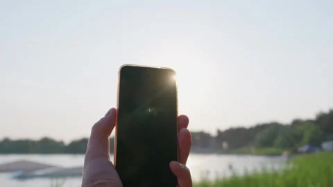 Hand Holding Smartphone with Blank Screen Outdoors Near Scenic Lake Sunset Stock-Footage 343562299