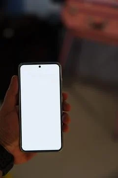 Hand holding smartphone with blank screen in indoor setting Stock Photos