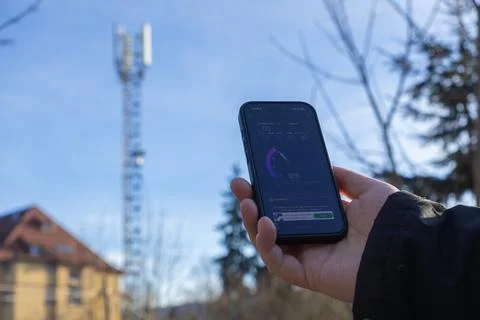 A hand holding a smartphone checking high mobile internet speed near a Foto stock