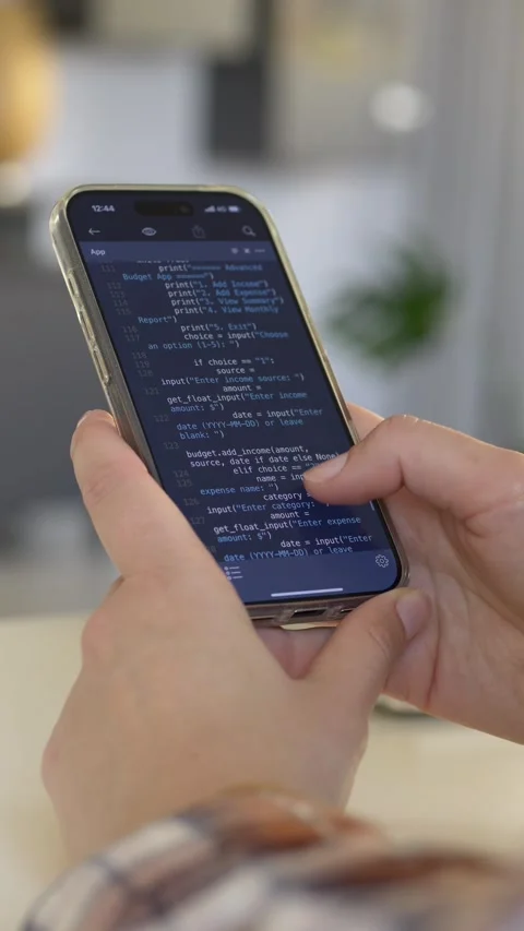 Hand holding smartphone with dark coding interface showing mobile development Stock Footage 331010386