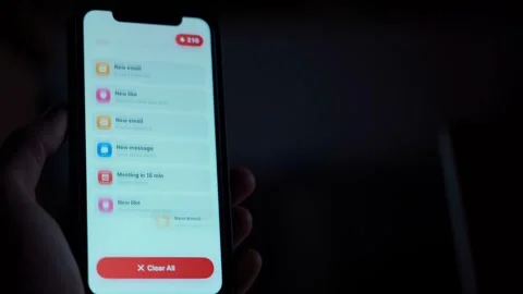 Hand holding smartphone in the dark receiving many notifications close-up Видео 340388471