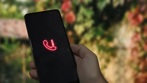 Hand holding a smartphone displaying a glowing red telephone icon with an ex Stock Footage 340510103