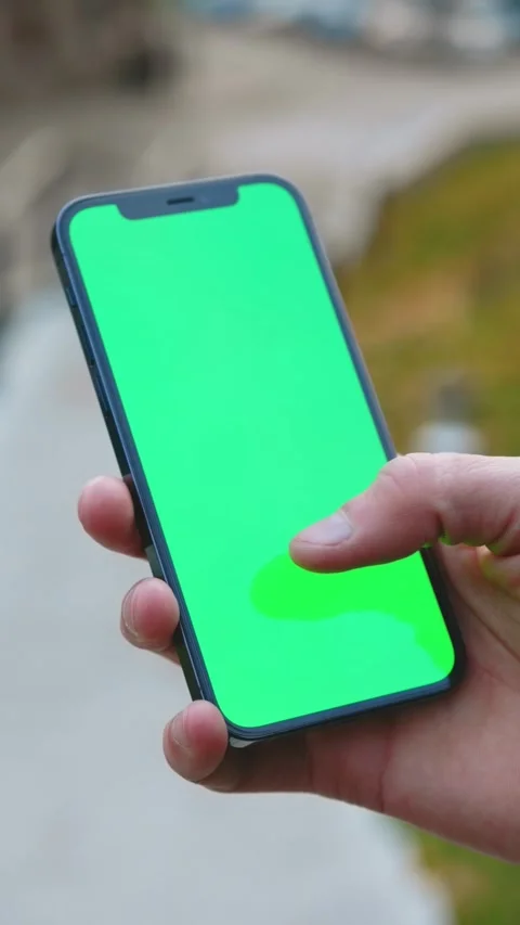 A hand is holding a smartphone featuring a green screen that can be customized Stock Footage 314150568