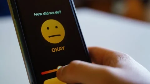 Hand holding smartphone with feedback app showing angry face and bad rating Stock Footage 339417717