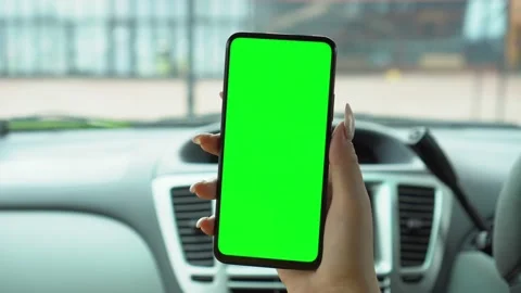 A hand holding a smartphone with green blank screen in the car for direction Stock Footage 142068053