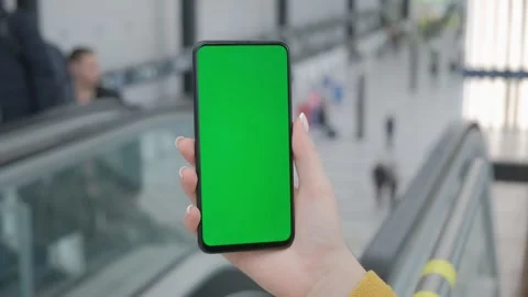 Hand Holding Smartphone with Green Screen in Airport Terminal Stock Footage 277216971