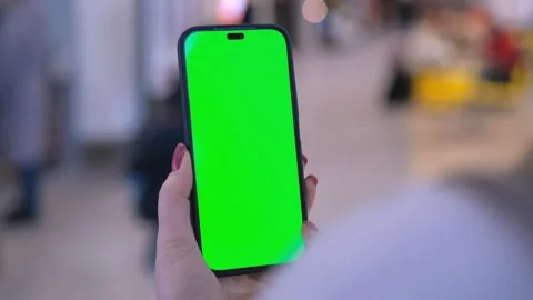 Hand holding smartphone with green screen in bright office, representing digital Stock Footage 277968353