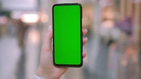 Hand holding smartphone with green screen, perfect for mockups or chroma key Video stock 278023302