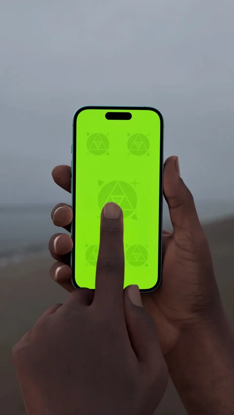 Hand holding smartphone with green screen by the beach on an overcast day Stock Footage 295209713