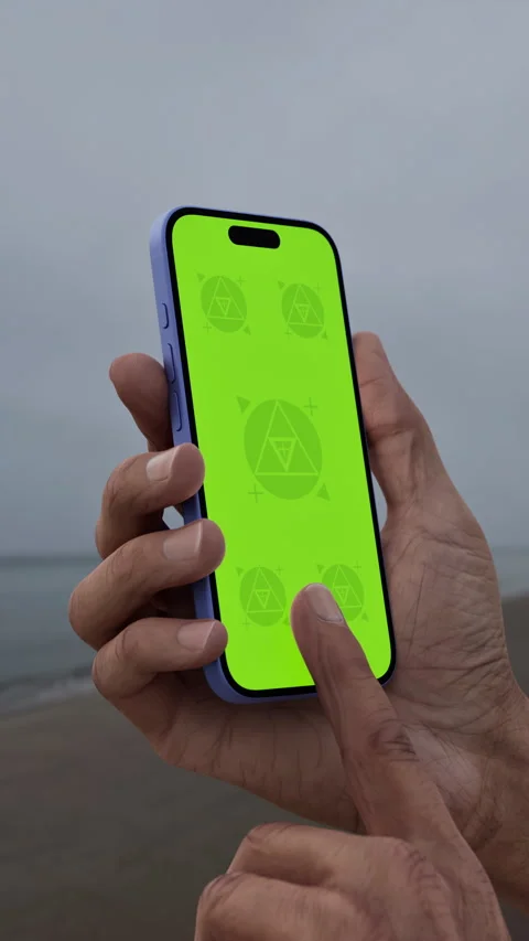 Hand holding smartphone with green screen by the beach on an overcast day Stock Footage 295209722