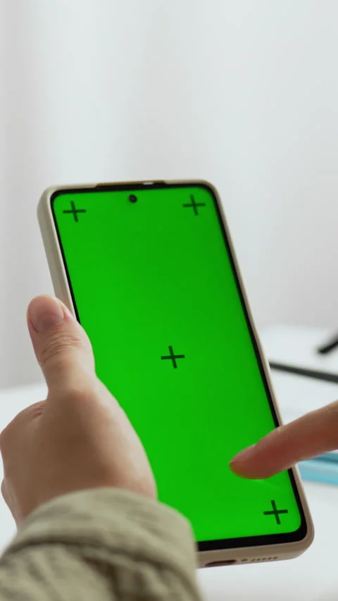 Hand holding a smartphone with a green screen ready for app development in a Stock Footage 331594385