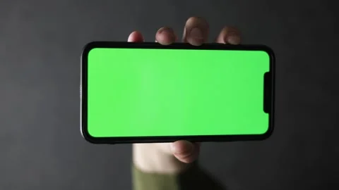 Hand holding smartphone with green screen for easy keying and customization Stock Footage 339217545