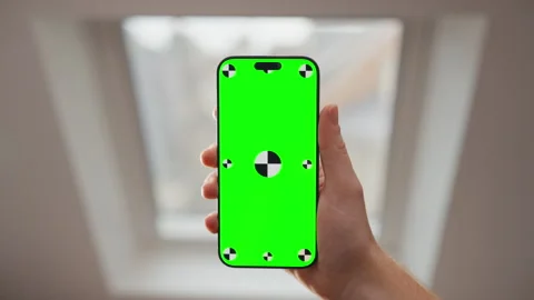 Hand Holding Smartphone with Green Screen Mockup by Window in Bright Indoor Stock Footage 345846902