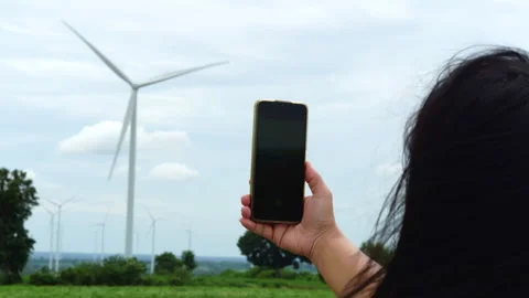Hand holding smartphone mockup with blank black screen in wind turbine farm Video stock 342905976