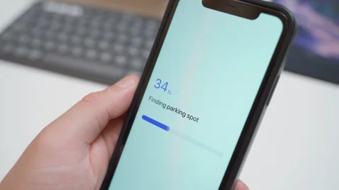 Hand holding smartphone with parking app searching for spot and showing no spots Stock Footage 342130270