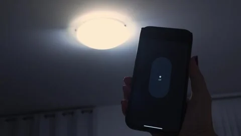 Hand holding smartphone with smart light control interface, transitioning from Stock Footage 332578521