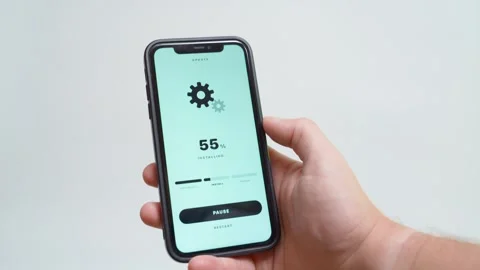 Hand holding smartphone with software update downloading at percent. Gear icon Stock Footage 342911662