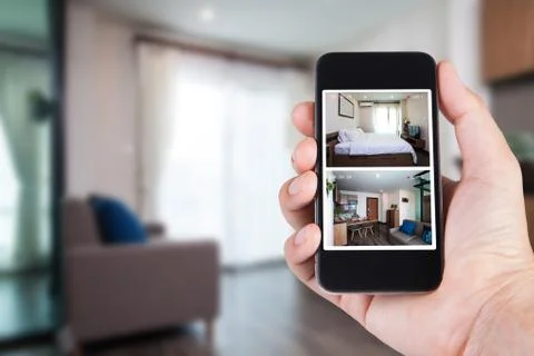Hand holding smartphone view looking in house on blurred house background wit Stock Photos