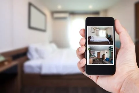 Hand holding smartphone view looking in house on blurred house background wit Stock Photos