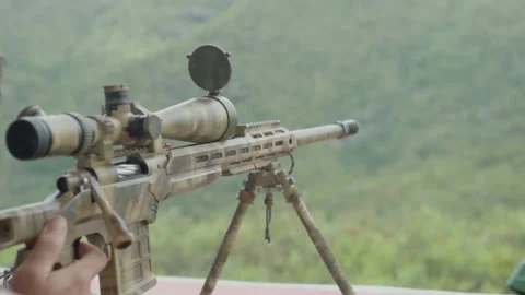A hand holding a sniper rifle trigger, as it discharges and lets out a puff of Stock Footage 332958793