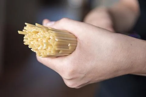 Hand holding spaghetti close-up. The process of cooking Italian spaghetti. Stock Photos