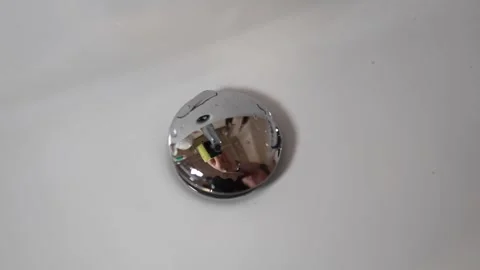 Hand holding sponge reflected in shiny sink drain cleaning in progress soft drop Stock Footage 309334323