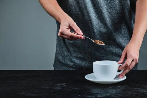 Hand holding spoon full of coffee on the dark background Stock Photos