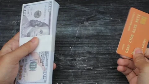 Hand holding a stack of dollar bills and credit card isolated black board Stock Footage 309898037