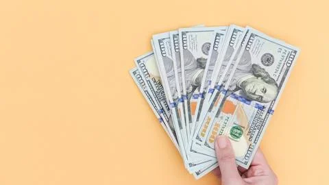 Hand Holding a Stack of Hundred Dollar Bills Isolated on a Neutral Background Stock Photos
