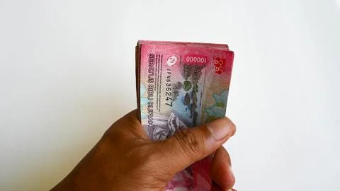Hand Holding Stack of Indonesian Rupiah 100000 Banknotes on White Background 스톡 사진