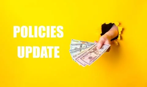 Hand holding a stack of money with the words Policies Update written below Stock Photos