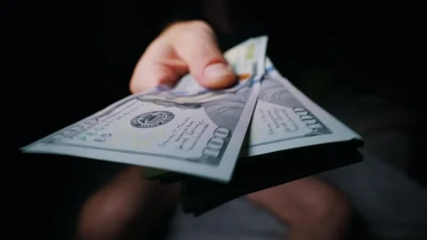 Hand Holding Stack of One Hundred Dollar Bills Towards Camera in Dark Room Stock Footage 339366530
