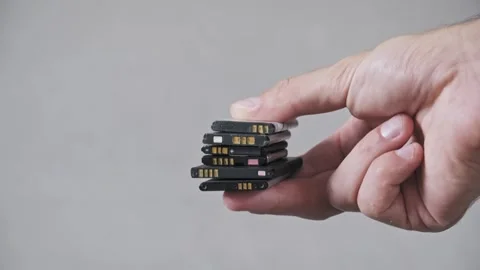 Hand Holding a Stack of Used Lithium-Ion Mobile Phone Batteries Stock Footage 316552699