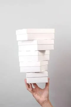 Hand holding a stack of white empty boxes against a gray background Foto stock