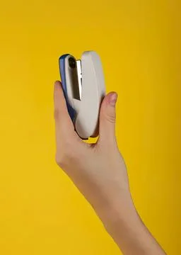 Hand holding a stapler on yellow background Stock Photos